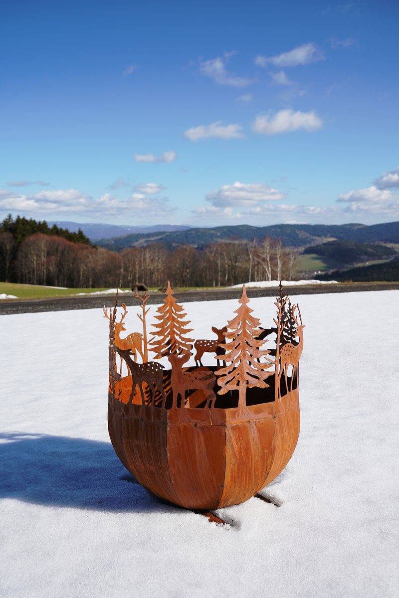 Feuerstelle im Schnee vor einer Hügellandschaft